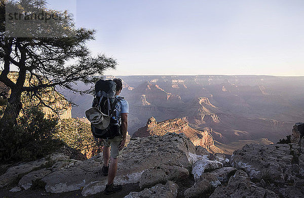 Rückansicht eines Mannes mit Rucksack  der auf einem Berg am Grand Canyon steht