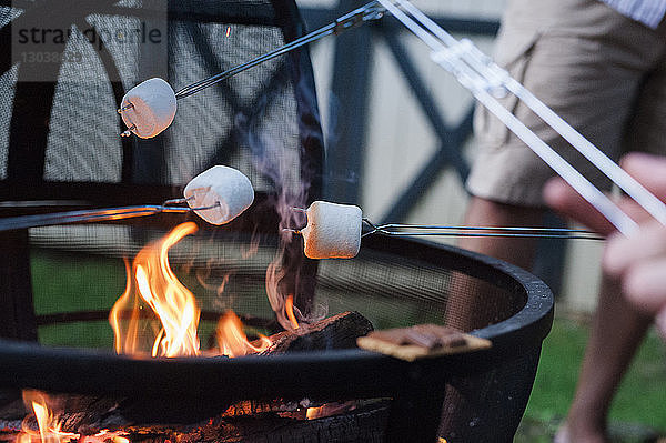 Ein Mann röstet Marshmallow am Lagerfeuer im Hof