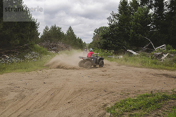 Geschwister fahren Quads auf dem Feld