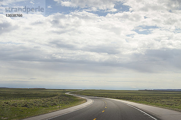 Landstraße mitten im Feld gegen bewölkten Himmel im Yellowstone-Nationalpark