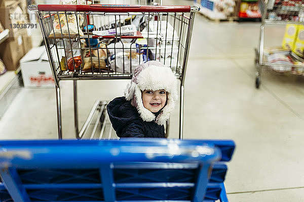 Hochwinkelporträt eines süßen Mädchens mit Einkaufswagen im Supermarkt