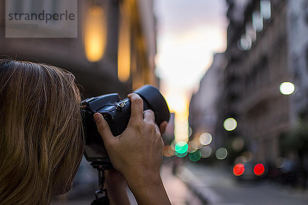 Beschnittenes Bild einer Frau  die in der Stadt mit einer Digitalkamera fotografiert