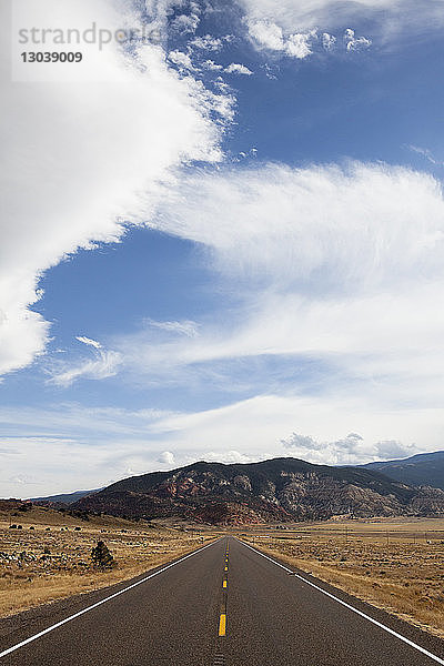 Landstraße gegen Berge und bewölkten Himmel