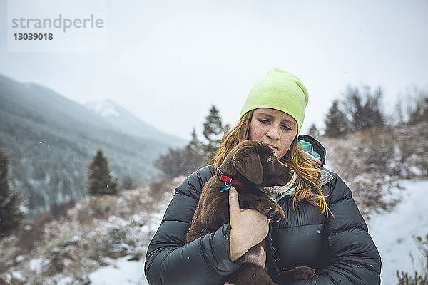 Frau mit Schokolade Labrador steht im Winter gegen den Himmel