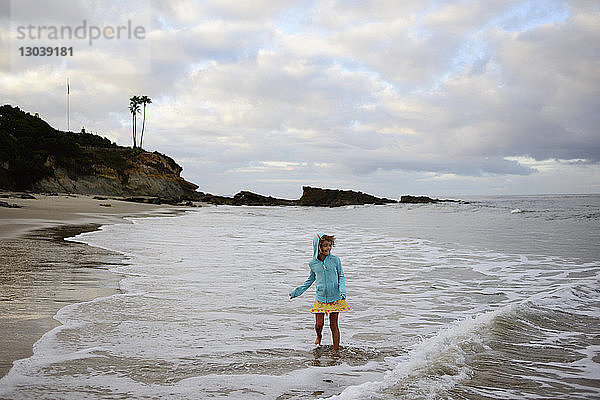 Mädchen spielt in Wellen am Laguna Beach gegen bewölkten Himmel