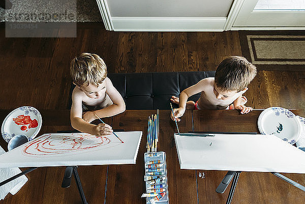 Draufsicht von Jungen ohne Hemd  die zu Hause auf Leinwand malen