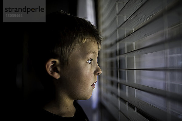 Nachdenklicher Junge schaut durch Fensterläden