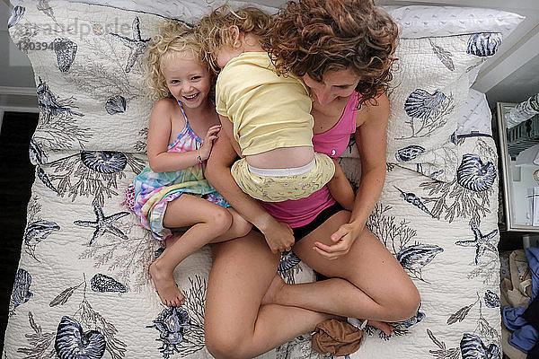 Hochwinkelaufnahme einer Mutter mit Töchtern  die zu Hause auf dem Bett sitzen