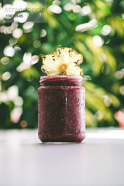 Nahaufnahme einer Ananasscheibe auf Konfitüre im Glas bei Tisch