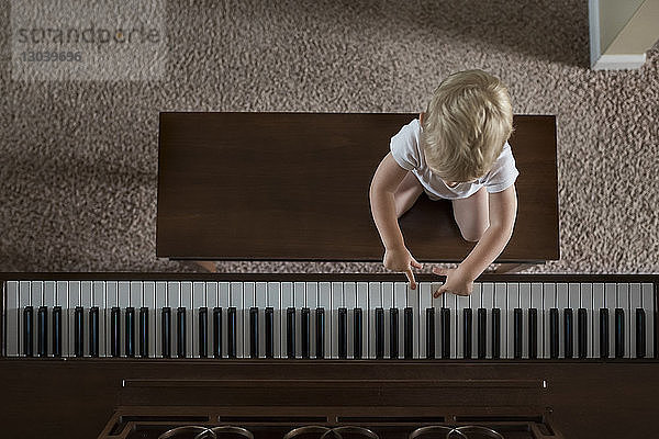 Draufsicht eines Jungen  der zu Hause Klavier spielt