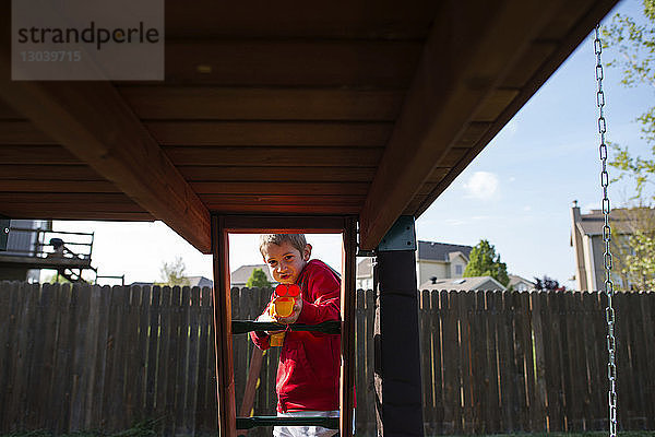 Porträt eines Jungen  der auf dem Spielplatz mit einer Spielzeugpistole spielt