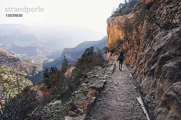Rückansicht eines Mannes  der auf einem Fußweg am Berg am Grand Canyon entlang geht
