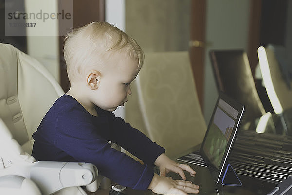 Seitenansicht eines Jungen  der einen Tablet-Computer betrachtet  während er auf einem Stuhl sitzt
