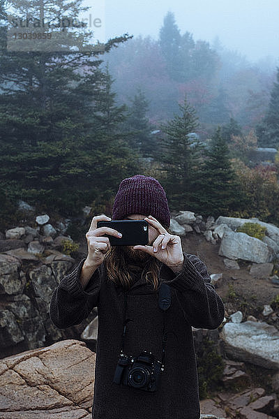 Frau  die im Winter mit dem Handy fotografiert