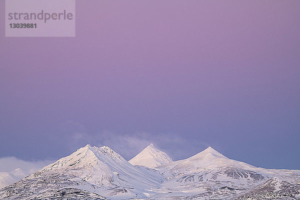 Szenische Ansicht schneebedeckter Berge vor dramatischem Himmel