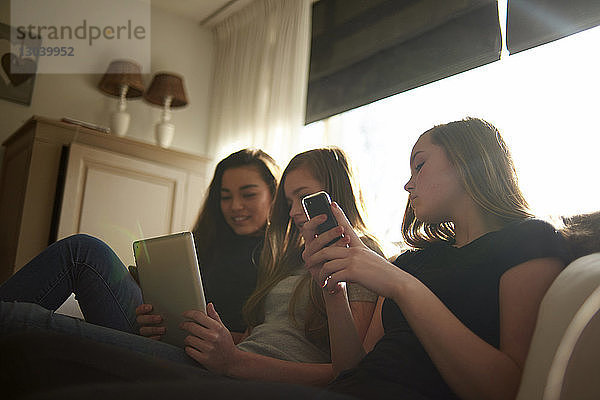 Niedriger Blickwinkel einer Teenagerin  die mit einem Tablet-Computer auf Freunde schaut