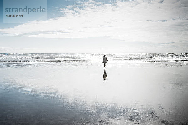 Rückansicht einer Frau  die am Strand spazieren geht
