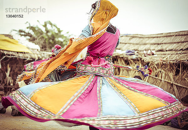 Frau in traditioneller Kleidung tanzt auf dem Feld