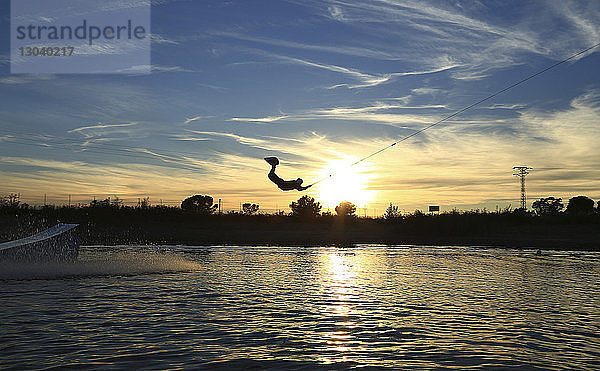 Silhouette eines Mannes beim Kitesurfen gegen den Himmel bei Sonnenuntergang