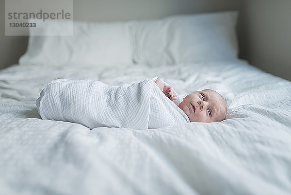 Seitenansicht eines neugeborenen Jungen  der weg schaut  während er zu Hause im Bett liegt