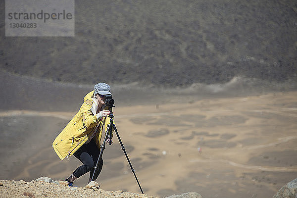 Frau fotografiert mit Kamera auf Stativ in der Wüste