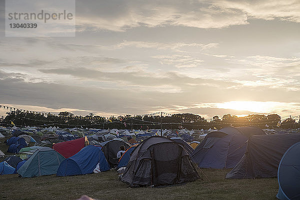 Zelte auf dem Feld gegen bewölkten Himmel auf dem Campingplatz bei Sonnenuntergang