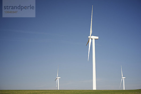 Windmühlen auf Grasfeld gegen blauen Himmel