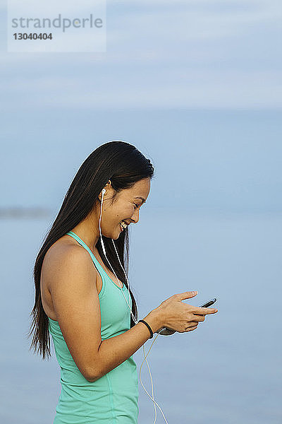 Glückliche Frau hört Musik  während sie ein Smartphone benutzt