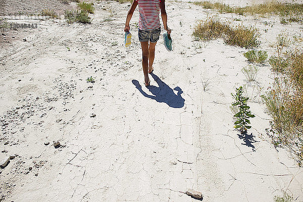 Rückansicht eines Mädchens mit Schuhen beim Spaziergang auf dem Feld im Badlands-Nationalpark