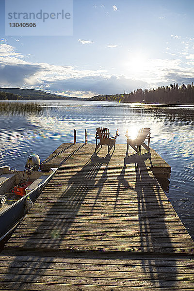 Stühle auf Holzsteg über dem See gegen den Himmel bei Sonnenuntergang
