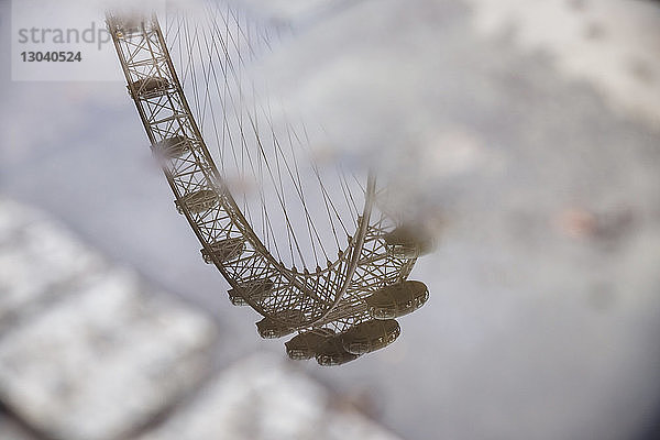 Spiegelung des London Eye in einer Pfütze auf einem Fußweg