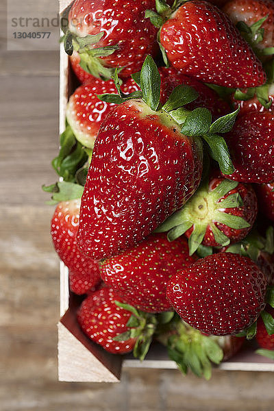 Draufsicht auf Erdbeeren in Kiste auf Holztisch