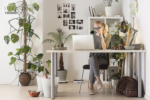 Kreative Geschäftsfrau in voller Länge mit Laptop im Büro