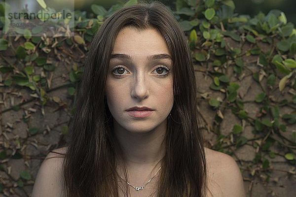 Porträt eines Teenager-Mädchens an Efeumauer stehend