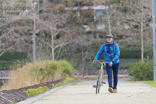 Mann mit Fahrrad auf Fußweg im Park