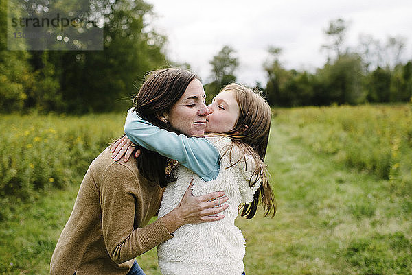 Tochter küsst Mutter  während sie im Winter im Park steht