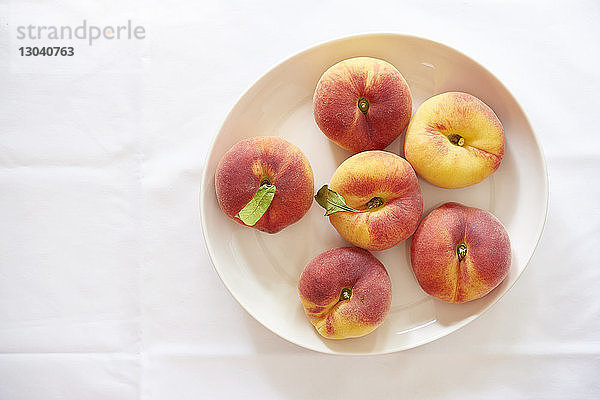 Draufsicht auf Pfirsiche in Tellerform über weißem Hintergrund