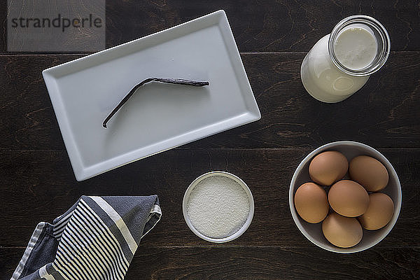 Draufsicht auf Vanillestange im Tablett bei Eiern und Milch auf dem Tisch