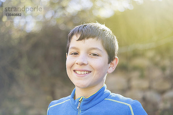 Porträt eines fröhlichen Jungen im Wald bei Sonnenschein