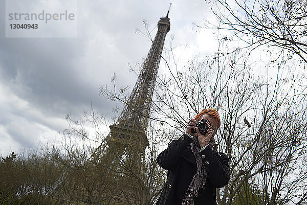 Niedriger Blickwinkel eines Fotografen mit Digitalkamera gegen den Eiffelturm