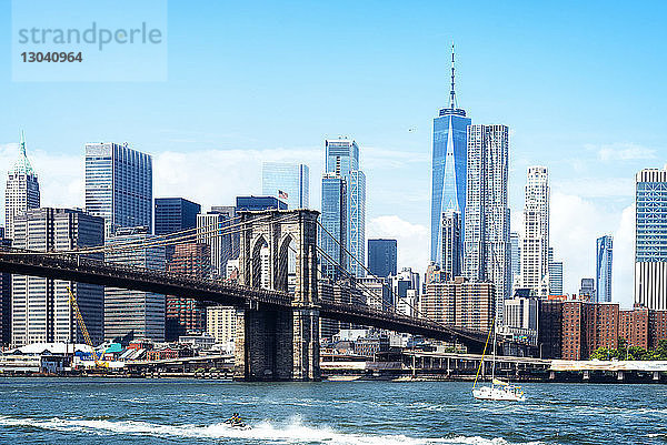 Brooklyn Bridge über den East River gegen das moderne Stadtbild bei sonnigem Wetter