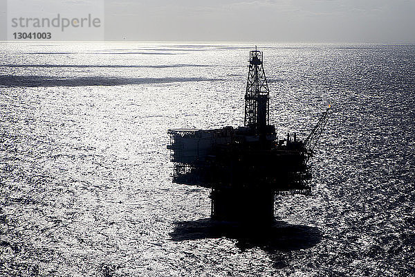 Silhouette einer Ölplattform im Meer an einem sonnigen Tag