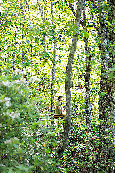 Wanderer schaut weg  während er mitten im Wald steht