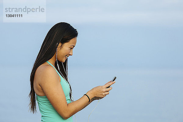 Glückliche Frau benutzt Smartphone beim Musikhören