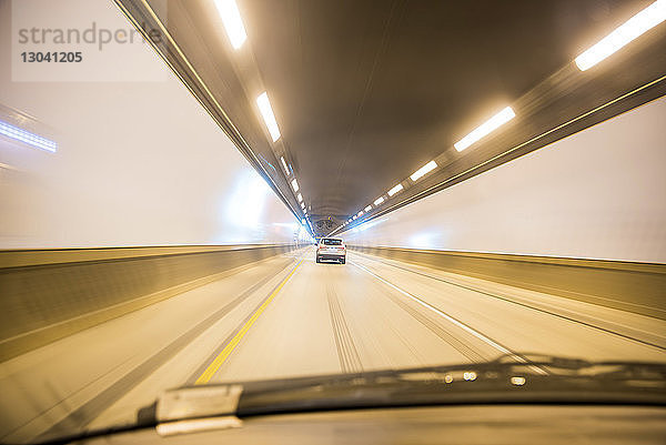 Auto fährt im beleuchteten Tunnel durch die Windschutzscheibe gesehen