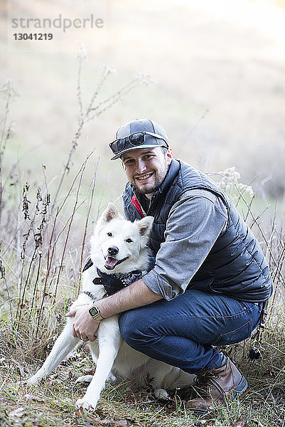 Porträt eines Mannes mit Hund auf dem Feld kauernd