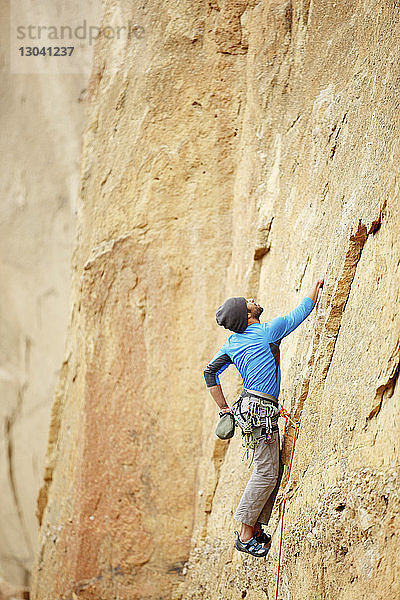 Männlicher Bergsteiger schaut beim Bergsteigen nach oben