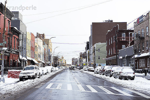 Straße inmitten von Gebäuden gegen den Himmel im Winter