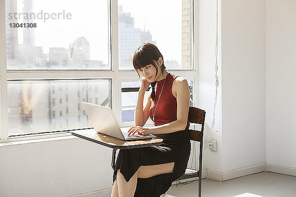 Seitenansicht einer Geschäftsfrau  die am Laptop im Kreativbüro arbeitet