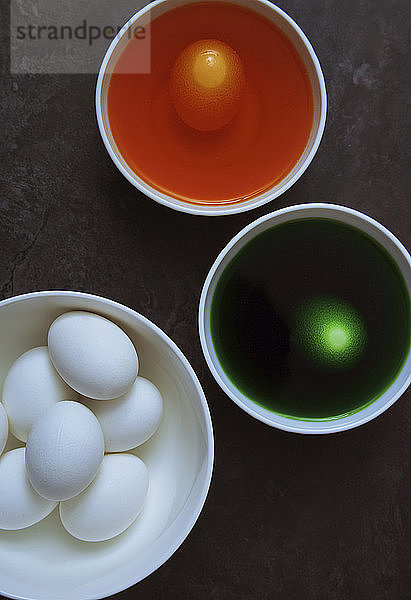 Draufsicht auf Eier und Lebensmittelfarbe in Schalen für die Osterdekoration auf dem Tisch